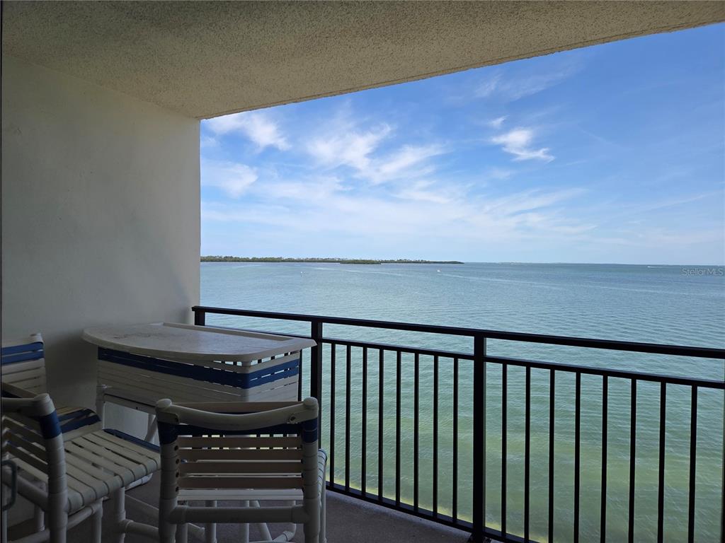 A balcony with patio furniture overlooks a wide expanse of water under a blue sky — 9 HAIG PLACE UNIT 405, DUNEDIN, FL