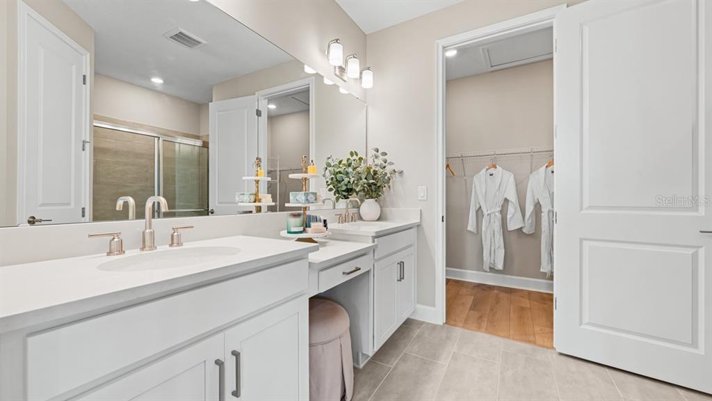 A kitchen with white cabinets and stainless steel appliances overlooks a breakfast bar with stools — 13340 SANTINI CIRCLE, ENGLEWOOD, FL