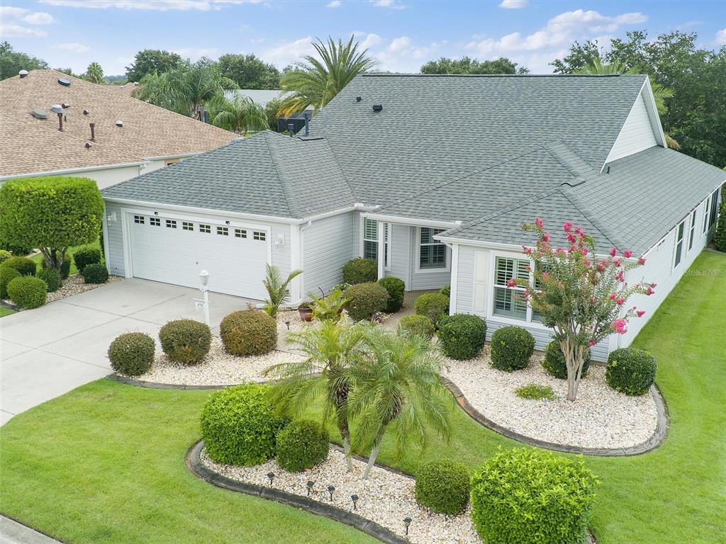 An aerial view of a single-story house with a green roof and landscaped front yard — 490 LITTLE RIVER PATH, THE VILLAGES, FL