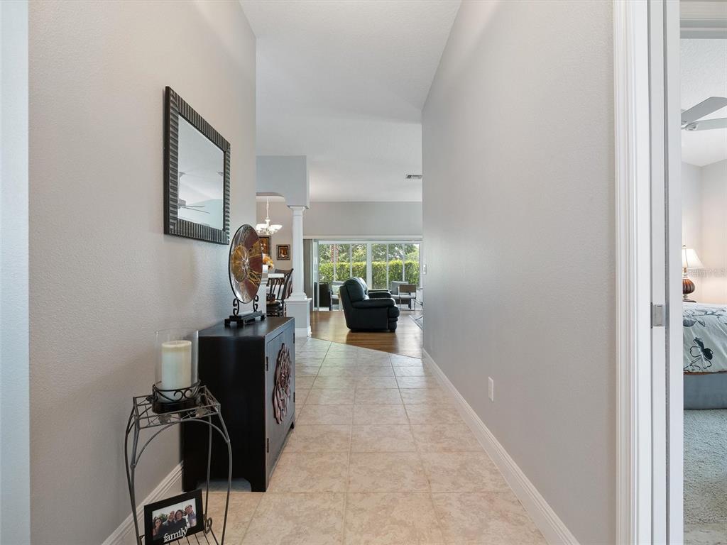 A tiled hallway leads from an entryway into a living area with a black recliner — 490 LITTLE RIVER PATH, THE VILLAGES, FL