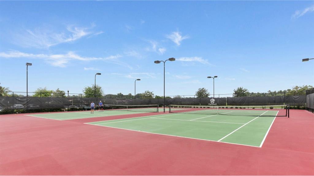Two outdoor tennis courts with green surfaces and red borders under a blue sky — 4493 OCHOS RIOS PLACE, KISSIMMEE, FL