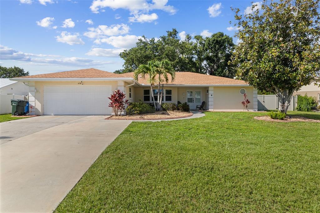 A single-story house with a tan exterior, a two-car garage, and a large front lawn — 5776 AUGUSTA CIRCLE, SARASOTA, FL