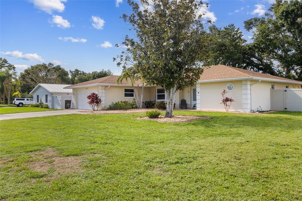 A single-story house with a beige exterior, a large front tree, and a grassy yard — 5776 AUGUSTA CIRCLE, SARASOTA, FL
