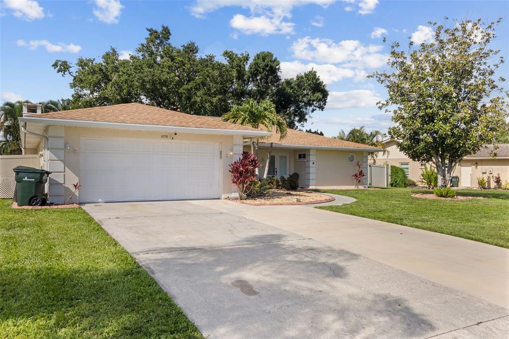 A single-story house with a beige exterior, a two-car garage, and a concrete driveway — 5776 AUGUSTA CIRCLE, SARASOTA, FL