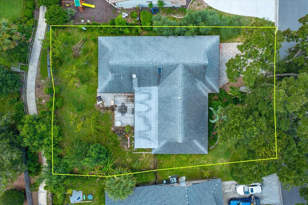 An aerial view shows a house with a gray roof, a wooden deck, and surrounding landscaping — 211 STEVENAGE DRIVE, LONGWOOD, FL