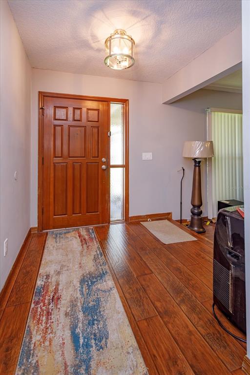 An entryway features a wooden front door, hardwood flooring, a runner rug, and a floor lamp — 211 STEVENAGE DRIVE, LONGWOOD, FL
