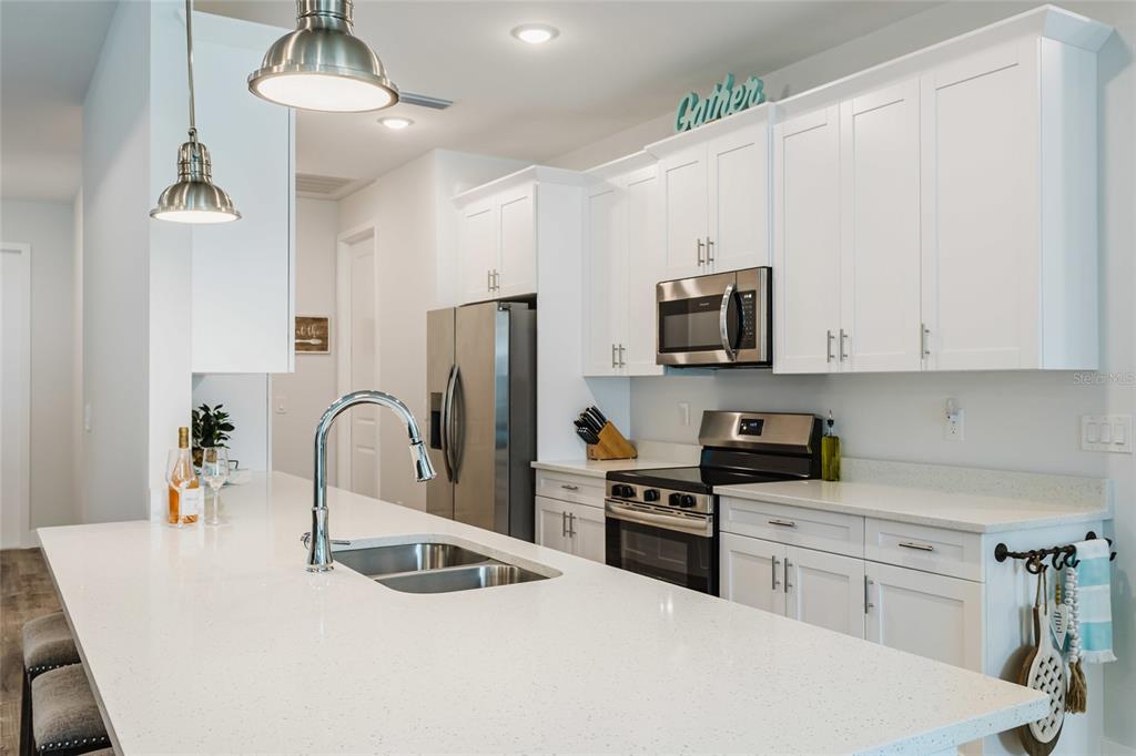 A single-story house with a three-car garage, light green siding, and a paved driveway — 908 HIBISCUS AVENUE, LEHIGH ACRES, FL