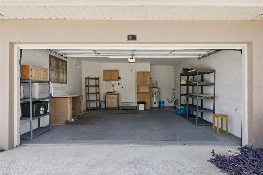 A garage with concrete block walls, storage shelving, a workbench, and a water heater — 815 CHESTNUT STREET, CLERMONT, FL