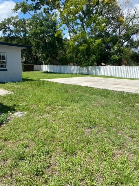 A grassy backyard features a concrete patio area enclosed by a white vinyl fence — 3100 EUNICE AVENUE, ORLANDO, FL
