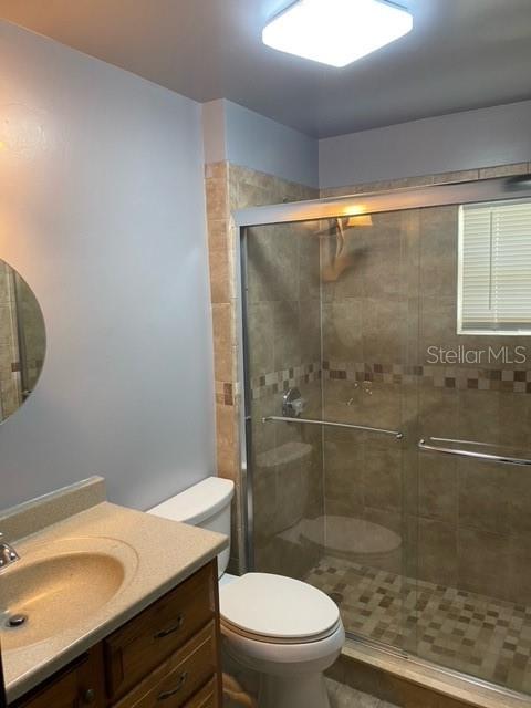 A bathroom features a vanity with a sink, a toilet, and a glass-enclosed tiled shower — 3100 EUNICE AVENUE, ORLANDO, FL