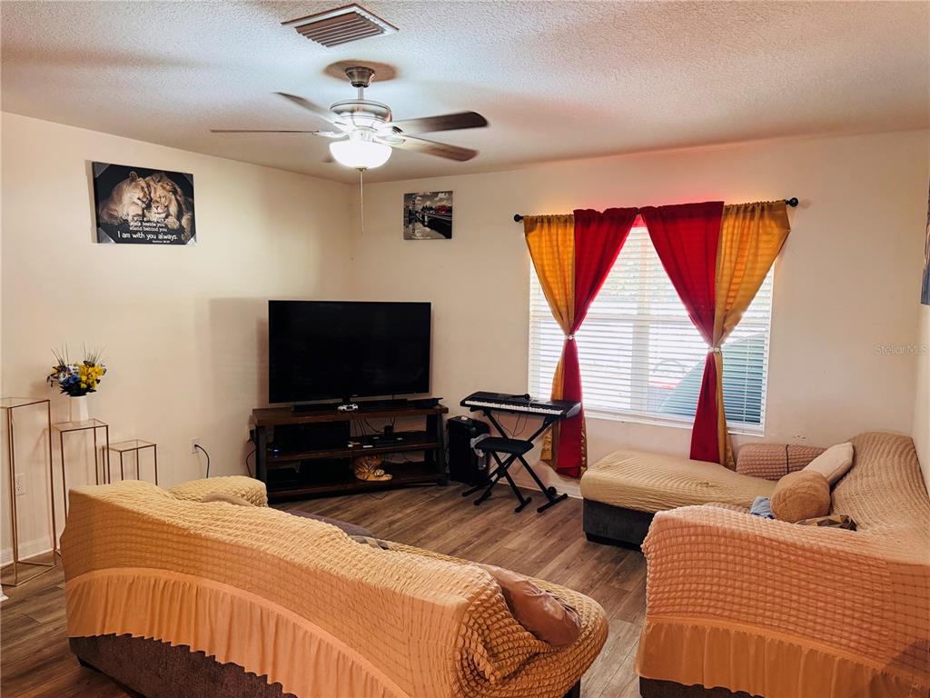 A living room features a television, a keyboard stand, and two sofas with textured covers — 3783 SE 97TH LANE, BELLEVIEW, FL