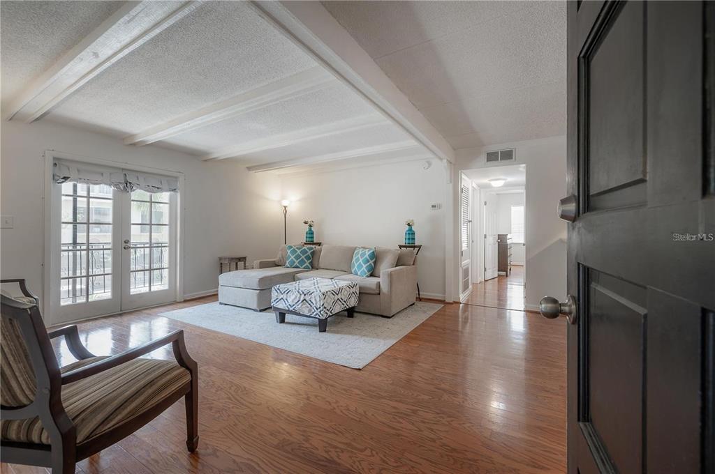 A living room with hardwood floors, a sectional sofa, and a view of a balcony — 107 S OBRIEN STREET UNIT 218, TAMPA, FL