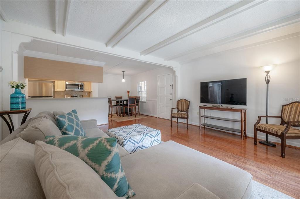 A living room with hardwood floors, a sectional sofa, a television, and an adjacent dining area — 107 S OBRIEN STREET UNIT 218, TAMPA, FL