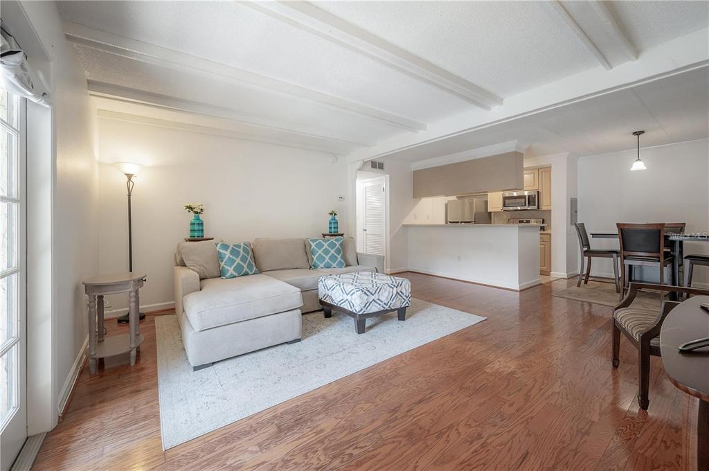 A living room with hardwood floors, a sectional sofa, and an open kitchen with bar seating — 107 S OBRIEN STREET UNIT 218, TAMPA, FL