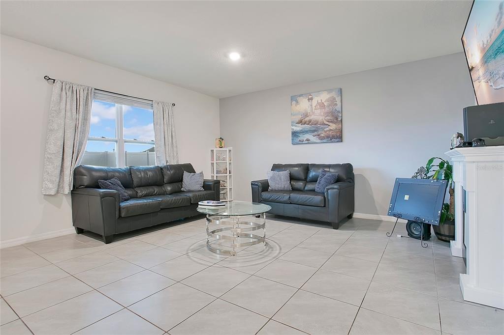 A living room features gray tile floors, two dark leather sofas, and a glass coffee table — 3676 SCARLET OAK DRIVE, ST CLOUD, FL