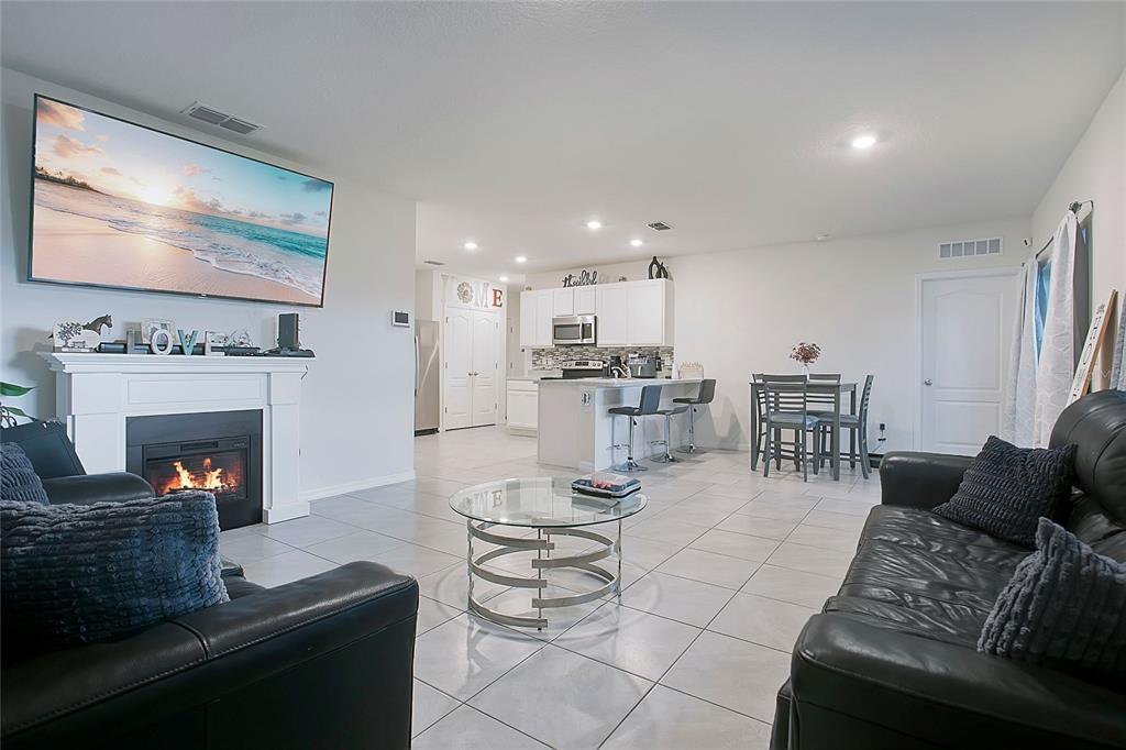 An open-concept living room features a fireplace, a television, and an adjacent kitchen with island — 3676 SCARLET OAK DRIVE, ST CLOUD, FL
