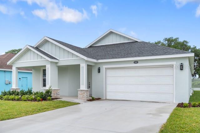 A light green single-story house with a two-car garage and a covered front porch — 4545 FAIRWAY OAKS DRIVE, MULBERRY, FL
