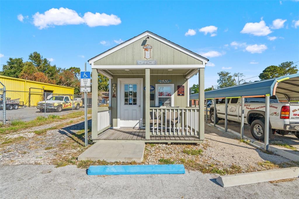 A small, light green office building with a front porch sits on a gravel lot — 9539 STATE ROAD 52, HUDSON, FL