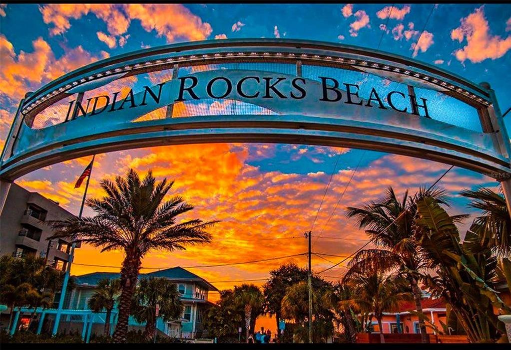 A sandy beach with dunes, ocean waves, and people under umbrellas under a blue sky — 372 12TH AVENUE, INDIAN ROCKS BEACH, FL
