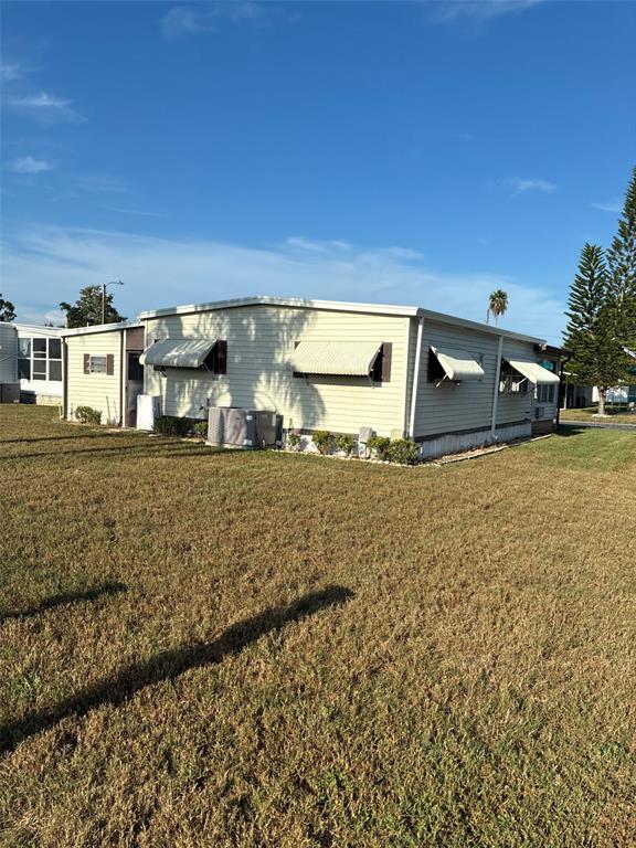The exterior of a mobile home features a carport, a screened porch, and light-colored siding — 3211 LANARK DRIVE, HOLIDAY, FL