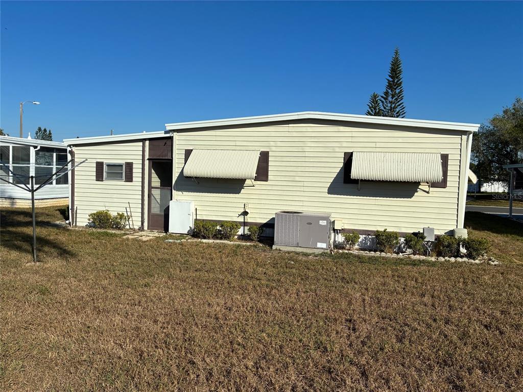 A mobile home exterior features a concrete carport, a covered entryway, and light-colored siding — 3211 LANARK DRIVE, HOLIDAY, FL