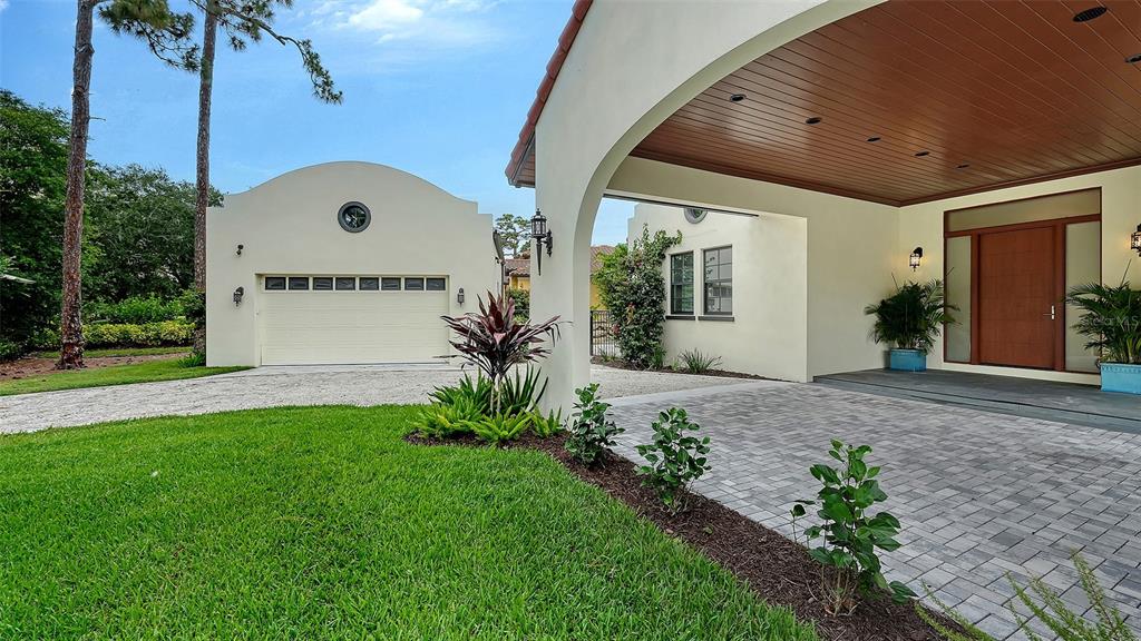 A paved driveway leads to a house entrance and a detached garage with arched architecture — 360 N POINT ROAD, OSPREY, FL