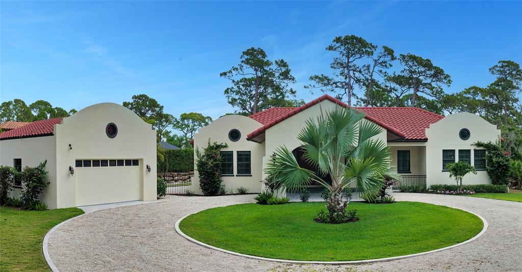 A single-story house with a red tile roof, arched parapets, and a circular gravel driveway — 360 N POINT ROAD, OSPREY, FL