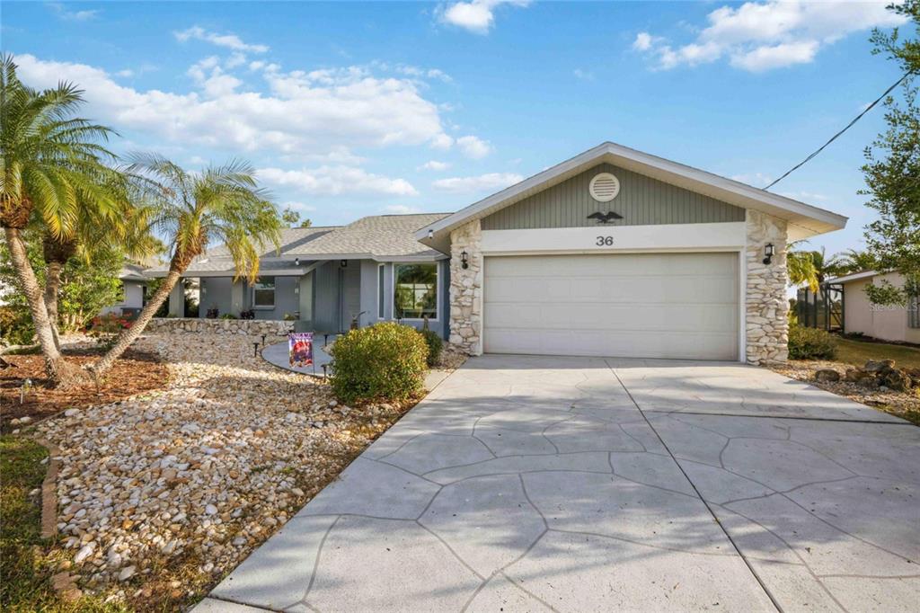 A single-story house with a stone-accented garage, a concrete driveway, and palm trees — 36 BUNKER CIRCLE, ROTONDA WEST, FL