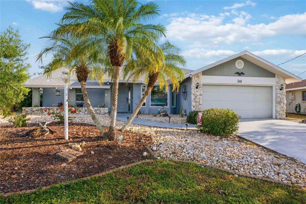A single-story house with a stone facade, a two-car garage, and a palm tree — 36 BUNKER CIRCLE, ROTONDA WEST, FL