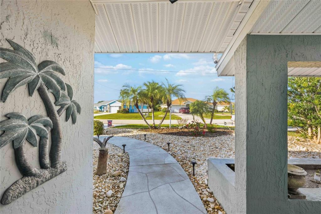 A view from a covered porch looking out onto a landscaped front yard and street — 36 BUNKER CIRCLE, ROTONDA WEST, FL