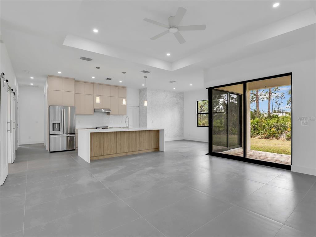 A modern kitchen with light wood cabinetry, a white island, and gray tile flooring — 11225 CARNEGIE AVENUE, ENGLEWOOD, FL