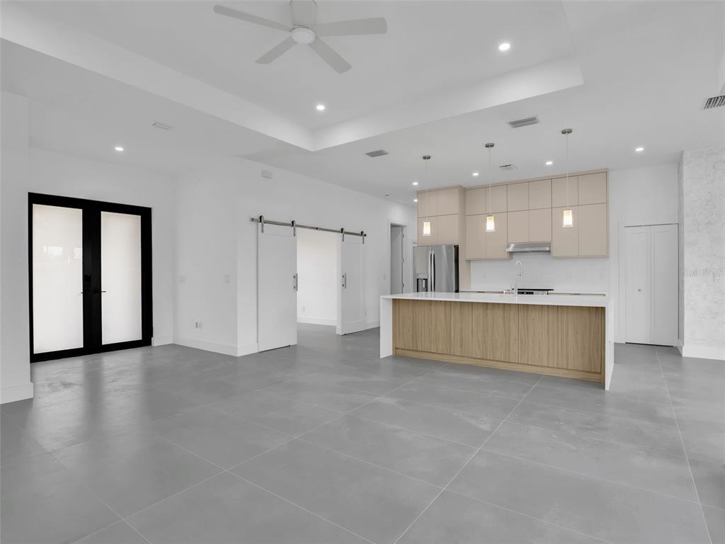 A modern kitchen and living area with gray tile floors, a wooden island, and white cabinetry — 11225 CARNEGIE AVENUE, ENGLEWOOD, FL