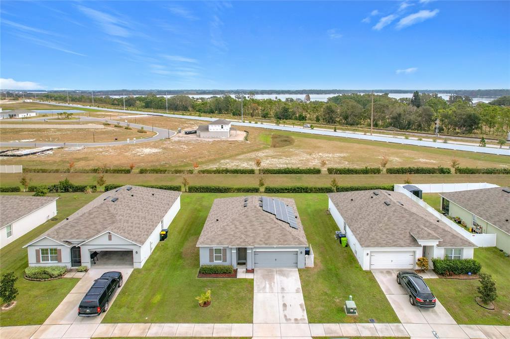 An aerial view shows three suburban houses with driveways and a large field behind them — 440 BURNHAM CIRCLE, AUBURNDALE, FL