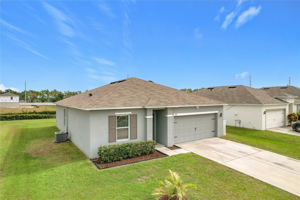 A single-story house with a gray stucco exterior, a shingled roof, and a two-car garage — 440 BURNHAM CIRCLE, AUBURNDALE, FL