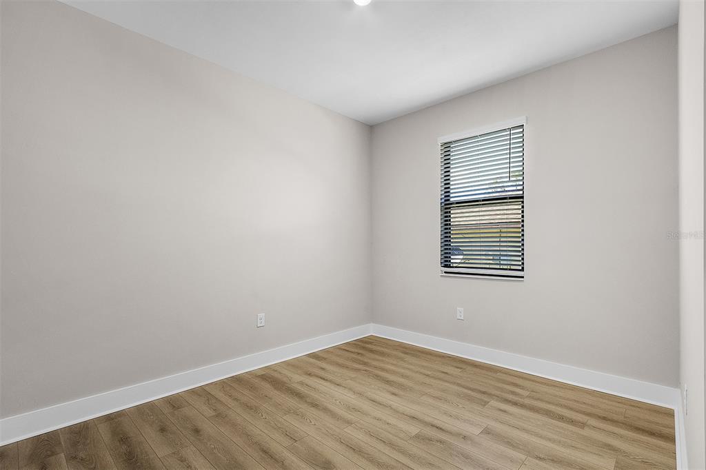 An empty bedroom features light gray walls, wood-look flooring, and a window with blinds — 13515 WALDEN SHEFFIELD ROAD, DOVER, FL
