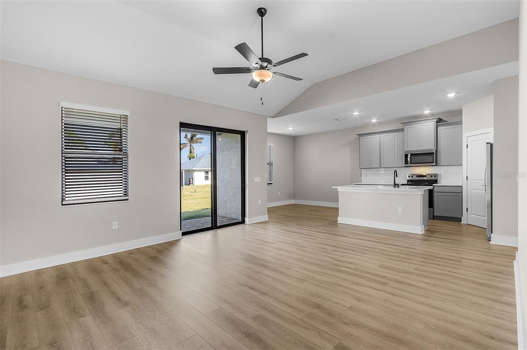 An open-concept living area features light wood-look flooring, a ceiling fan, and a modern kitchen — 13515 WALDEN SHEFFIELD ROAD, DOVER, FL