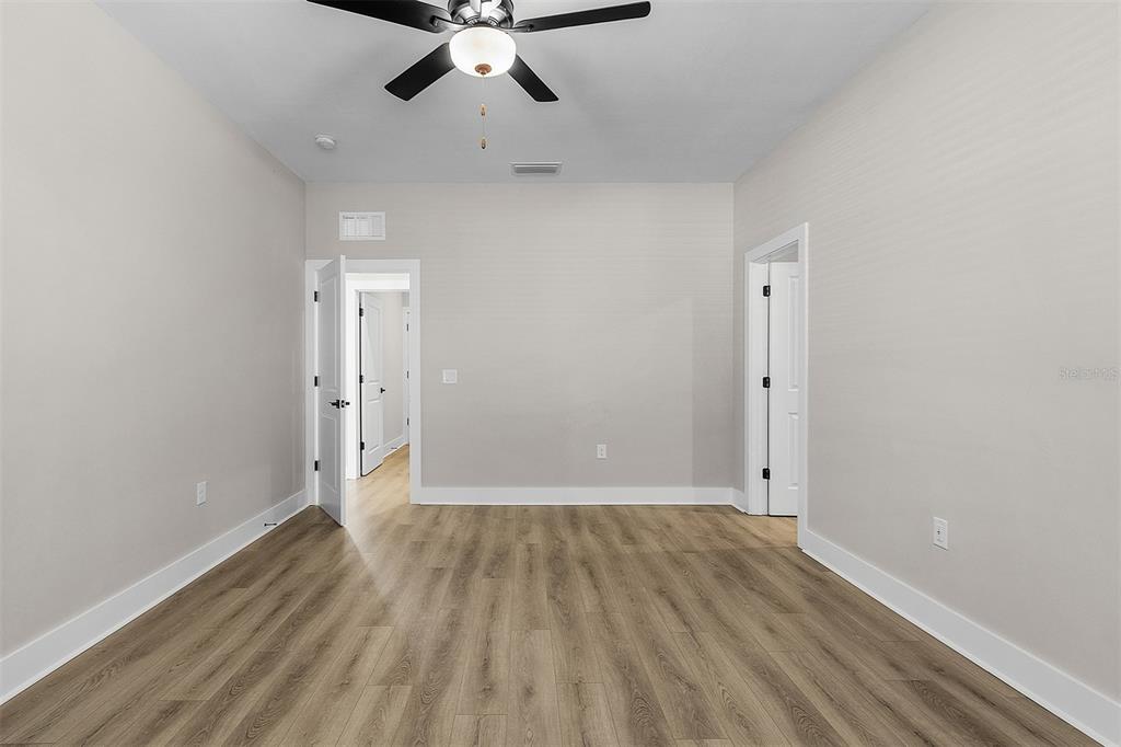 An empty room with light-colored walls, wood-look flooring, a ceiling fan, and two doorways — 13515 WALDEN SHEFFIELD ROAD, DOVER, FL