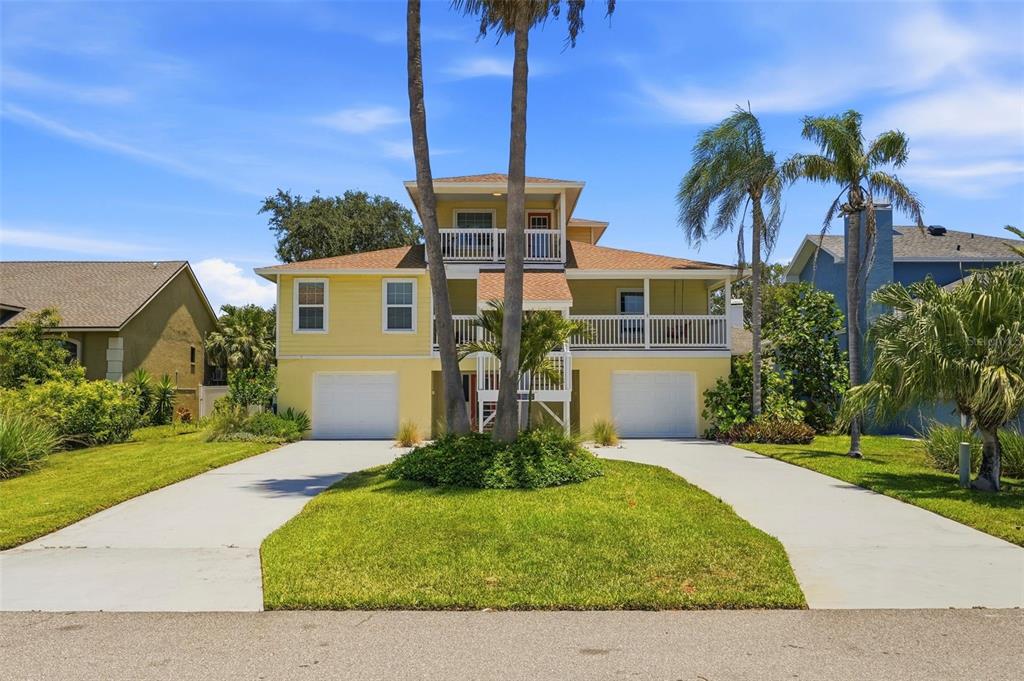 A yellow three-story house with two garages, a front porch, and two palm trees — 433 MONTE CRISTO BOULEVARD, TIERRA VERDE, FL
