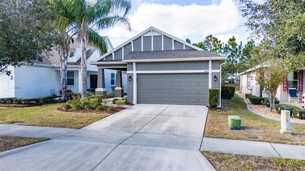 A gray single-story house with a two-car garage and a palm tree in the front yard — 3470 SAGEBRUSH STREET, HARMONY, FL