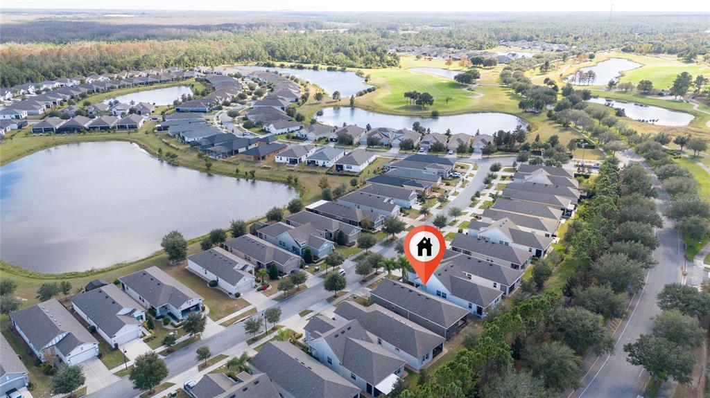 An aerial view shows a suburban neighborhood with houses, ponds, and a golf course — 3470 SAGEBRUSH STREET, HARMONY, FL