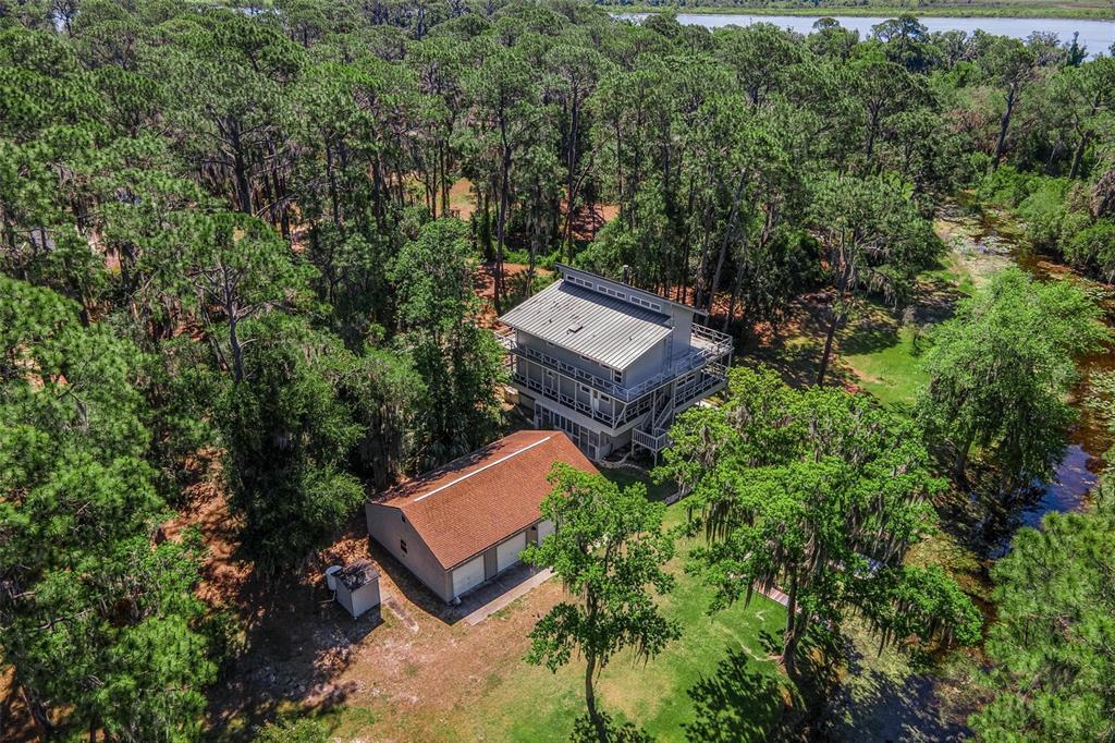 An aerial view shows a house with a metal roof and a detached garage nearby — 7373 CIRCLE DRIVE, LADY LAKE, FL