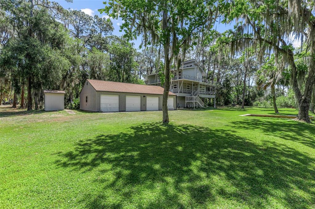A three-story house with a detached four-car garage sits on a large, grassy lot — 7373 CIRCLE DRIVE, LADY LAKE, FL