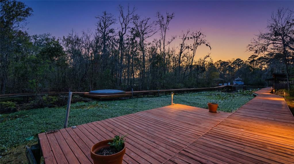 A wooden deck extends over a marshy area toward a treeline at sunset — 6595 COLLIER ROAD, ST AUGUSTINE, FL