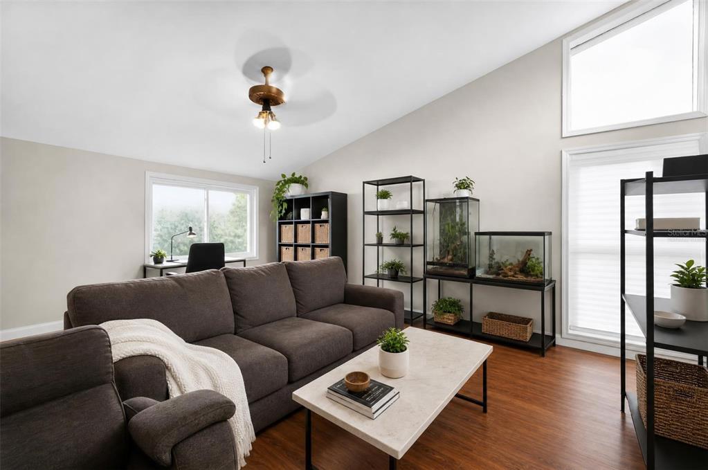 A living room features a dark sofa, a coffee table, shelving units, and a desk — 310 HIDDEN LAKE DRIVE, BRANDON, FL