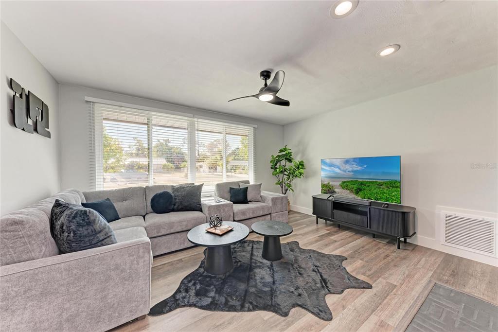 A living room features a grey sectional sofa, two round coffee tables, and a television — 339 SUWANEE AVENUE, SARASOTA, FL