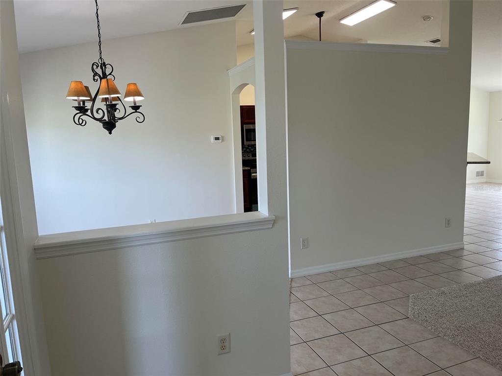 A spacious living room features vaulted ceilings, a ceiling fan, beige carpeting, and tiled flooring — 4949 SW 109TH LOOP, OCALA, FL