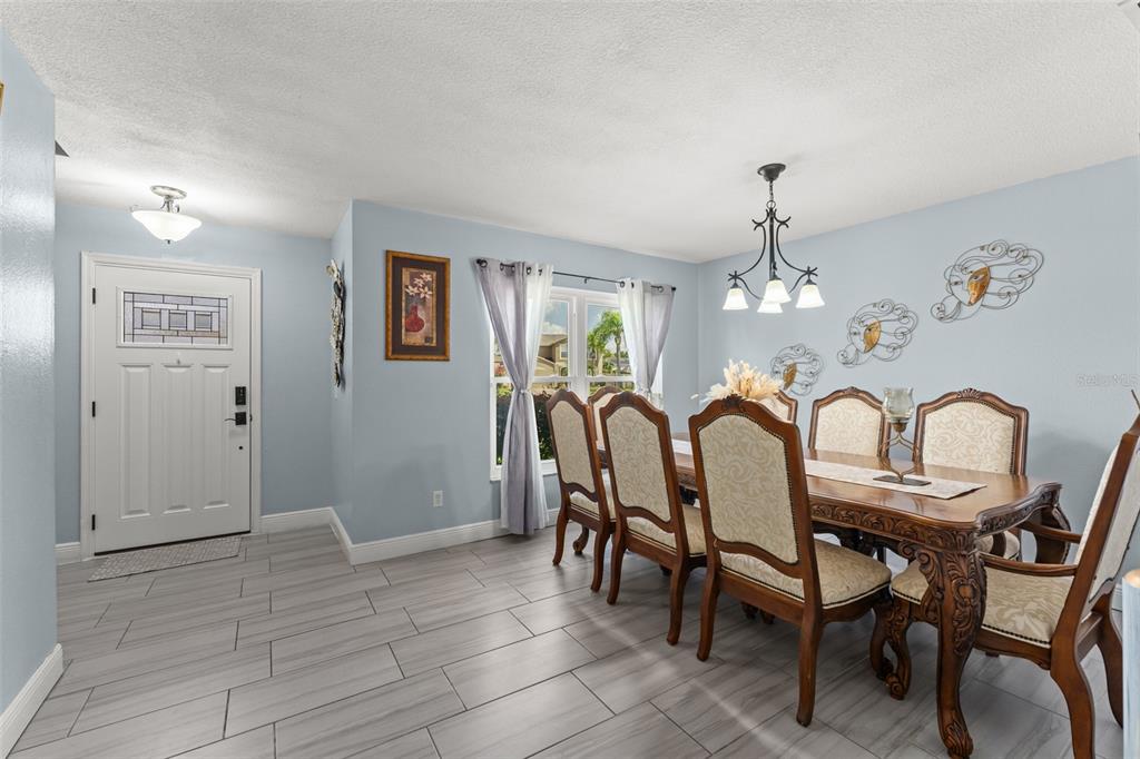 A dining room with light blue walls, wood furniture, and gray tile flooring — 15272 SUGARGROVE WAY, ORLANDO, FL