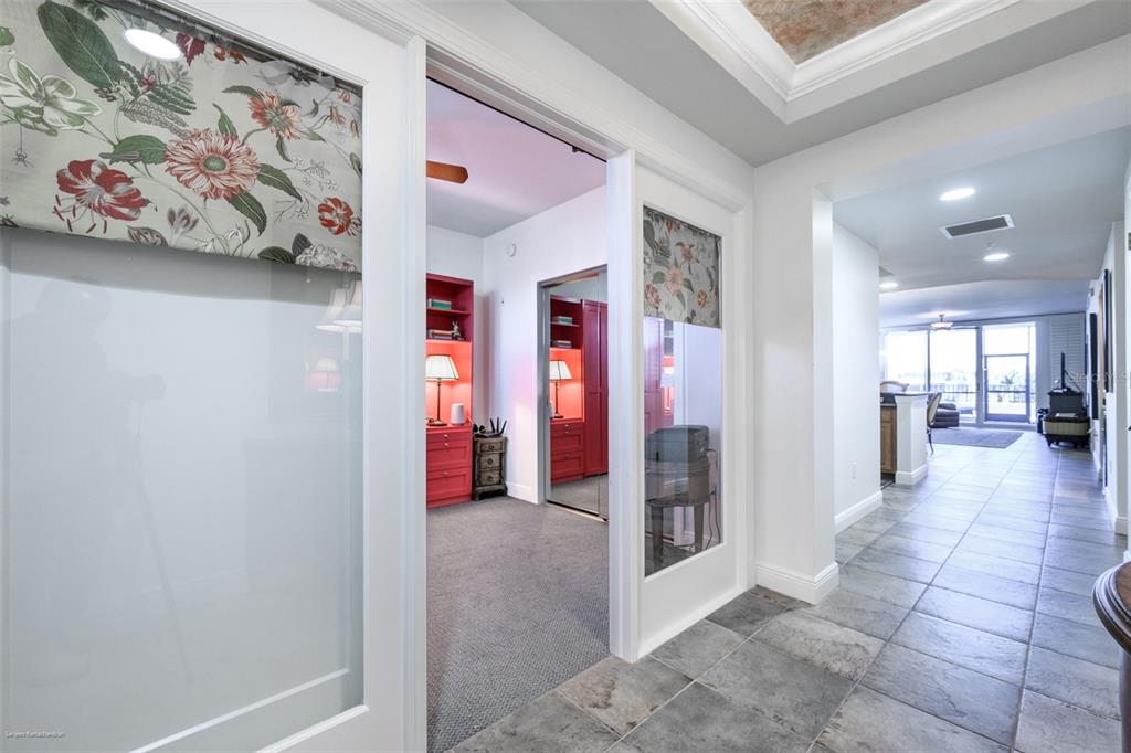 A hallway with tile flooring leads to a room with red cabinetry and glass doors — 3313 SUNSET KEY CIRCLE UNIT 104, PUNTA GORDA, FL