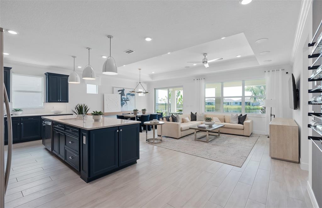 An open-concept kitchen and living area featuring dark blue cabinetry, a large island, and tile flooring — 1313 ZESTY CITRUS LANE, MINNEOLA, FL