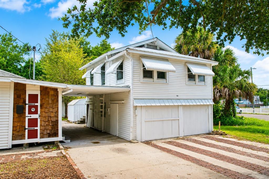 A two-story white house with a carport, garage doors, and a brick-accented side wall — 6506 N WELLINGTON AVENUE, TAMPA, FL